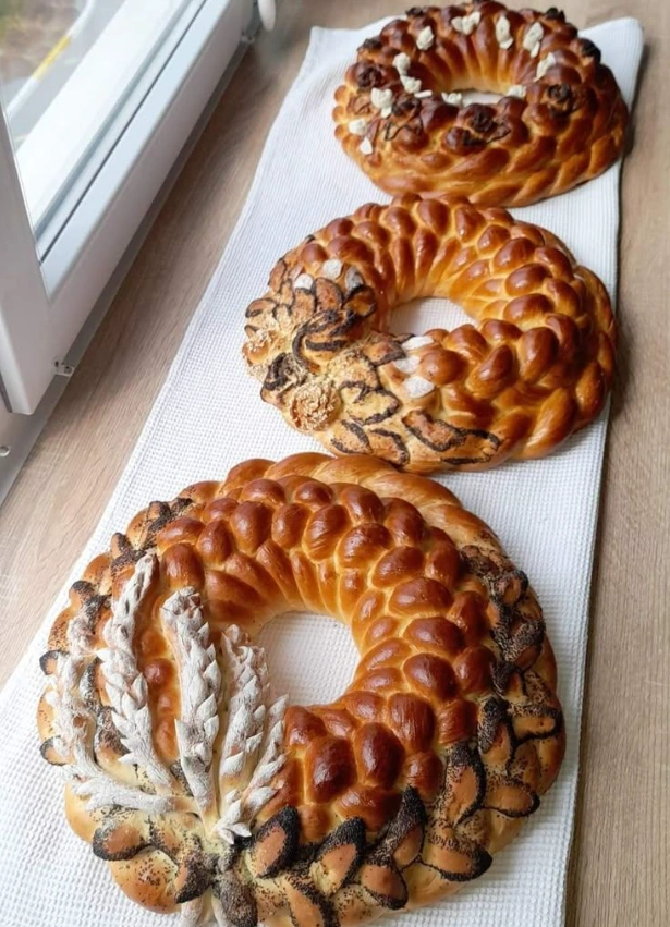 Три плетёных каравая-кольца с маком и колосьями на белом полотенце